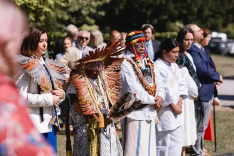 Delegates wearing traditional clothing listen to a speaker at the Harmony Summit.