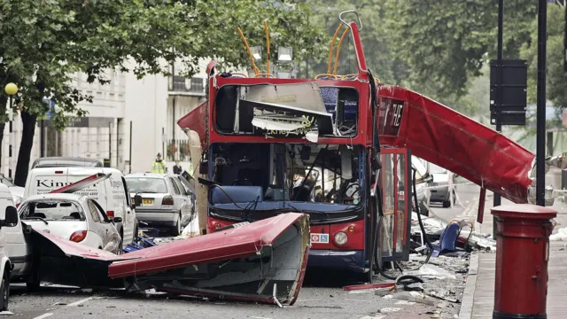 A bus in London with its roof damaged, surrounded by debris, following a bombing.