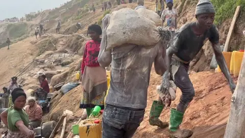 Miners and women selling goods at Rubaya mine in DR Congo.