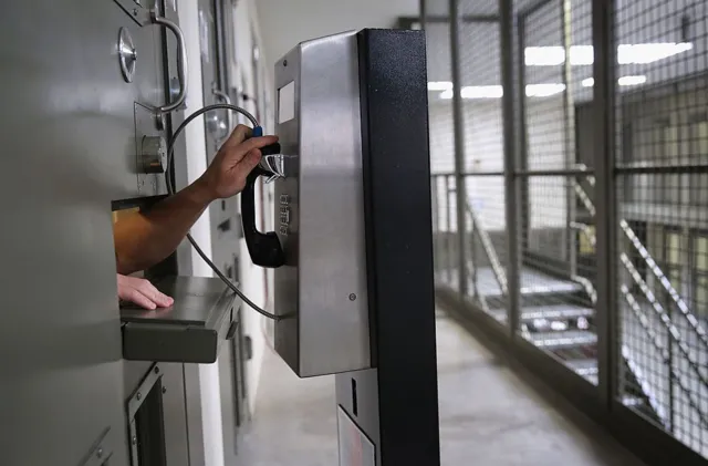 A file photo from November 2013 shows a detainee reaching for a payphone inside the Adelanto immigrant detention center.