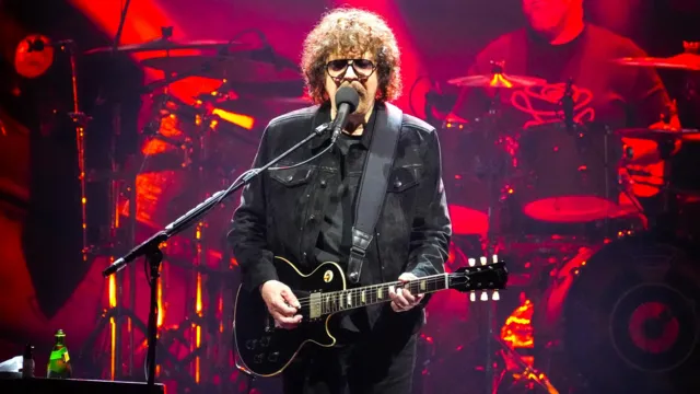 Jeff Lynne performing on stage with a guitar