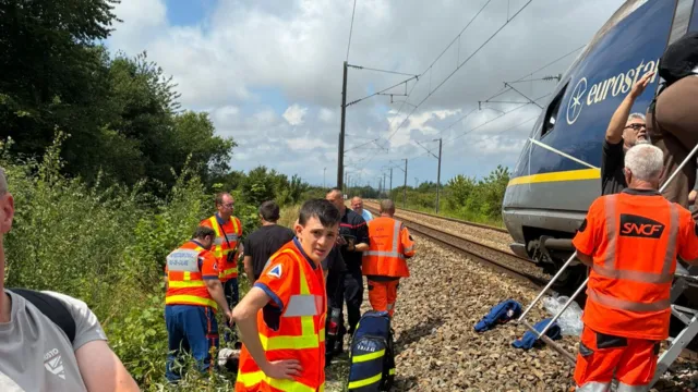 Rescue personnel assist passengers off a stationary Eurostar train in France.