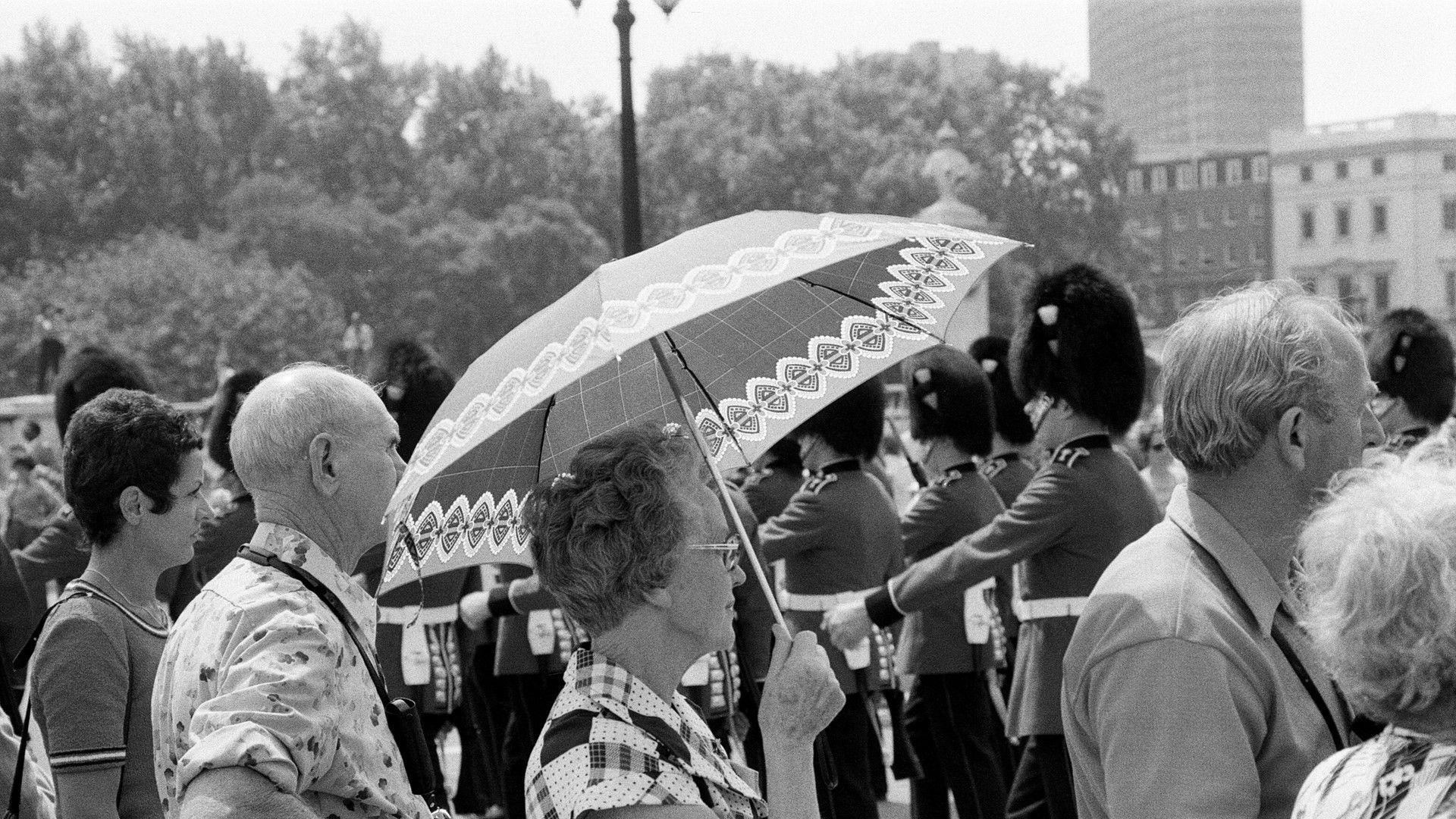 A historical black and white photograph of a crowd watching the Changing of the Guard in London during the 1976 heatwave.