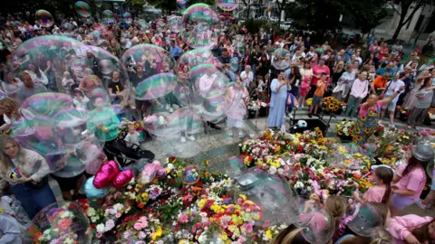 People blowing bubbles and leaving floral tributes outside Southport Town Hall in memory of the victims.