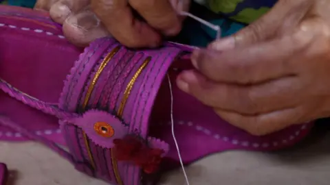 An artisan meticulously engraving a pattern onto a Kolhapuri slipper.
