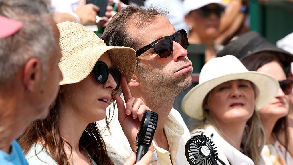 People using mini fans to stay cool during hot weather