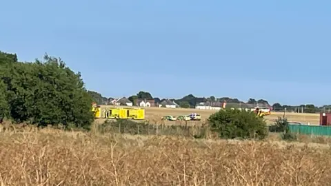 Emergency vehicles including ambulances and police cars at the scene of the incident near Southend Airport.