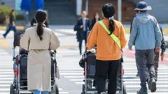 People seen with multi-seat strollers with babies in Gwanghwamun Square in the heart of Seoul.