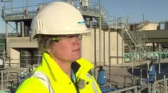 Yorkshire Water CEO Nicola Shaw in a helmet and high vis jacket stood in front of a sewage works