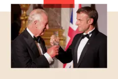 alt=Getty Images Macron and King Charles toast glasses, while looking happy and wearing black tie outfits