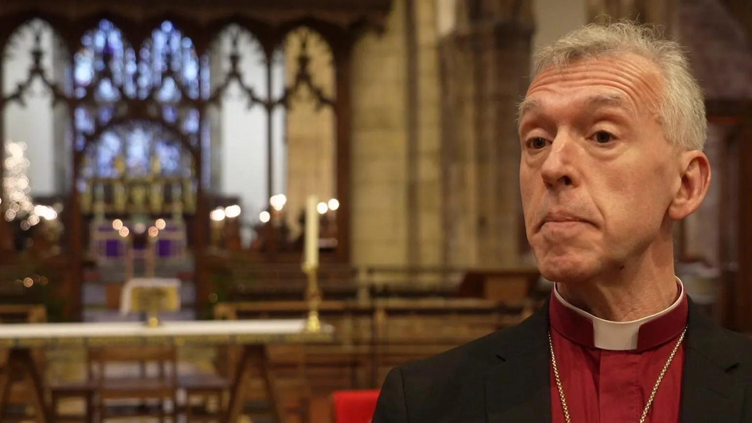 Andrew John, the outgoing Archbishop of Wales, wearing a purple top and dog collar inside a cathedral.