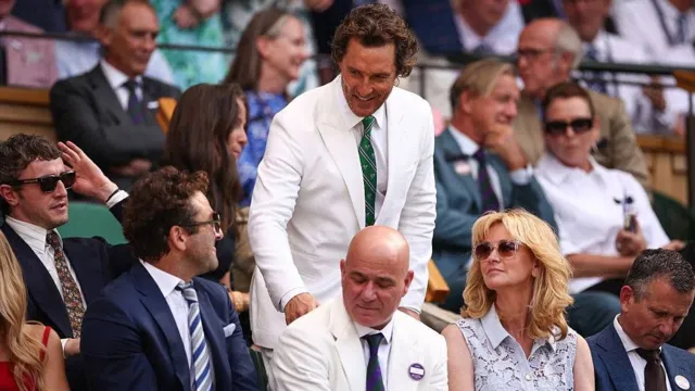 US actor Matthew McConaughey speaks with US former tennis player Andre Agassi as he arrives on the royal box on Centre Court.