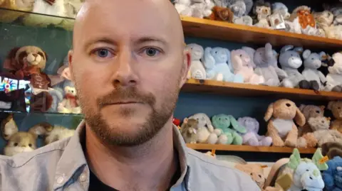 Joe Orrell, a key figure in the toy shop’s operation, stands proudly amidst the store’s vibrant atmosphere.