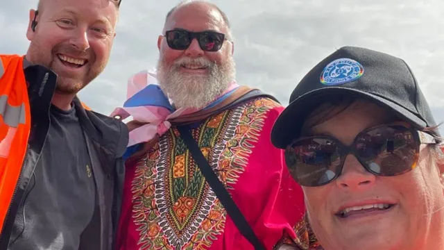 Alex MacDonald (left) with two other volunteers outside at a previous Plymouth Pride event.